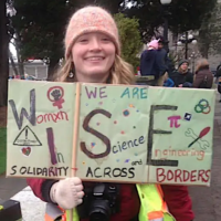 Thumbnail: Cayla Naumann with a sign WISE Women in Science and Engineering