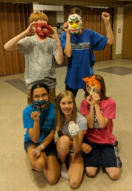 group of five young teenagers posing together with homemade masks